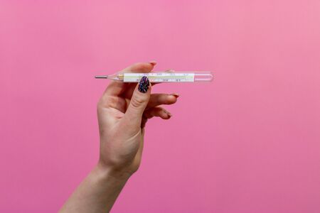 Closeup shot of Female hands holding a thermometer.