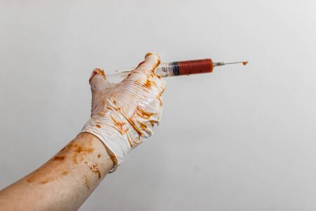 Doctor holds a syringe in latex gloves, gloves in the blood
