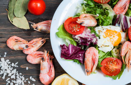 Healthy Shrimp and Arugula Salad with Tomatoes on a wooden table.の写真素材