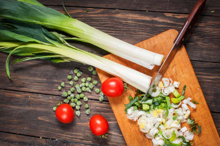 sliced fresh leek on wooden board with tomatoes.の写真素材