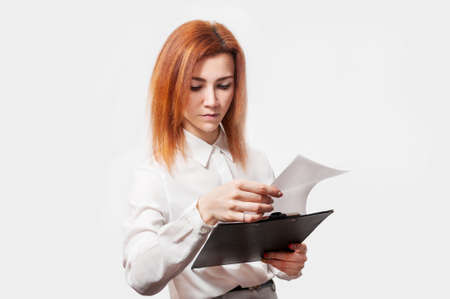 Young businesswoman with clipboard against white background.