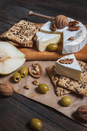 Camembert cheese with walnuts, honey and pears on rustic table.の写真素材