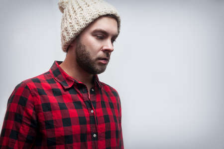Brutal bearded man wearing knitted cap and plaid shirt.