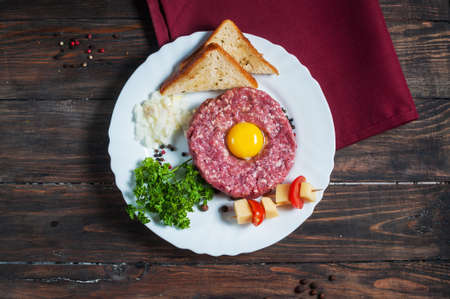Beef tartare with bread and fresh onion on a wooden background.の写真素材
