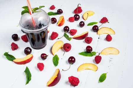 Various types of fruits with green leaves and frozen cocktail berries on white wood background.の写真素材