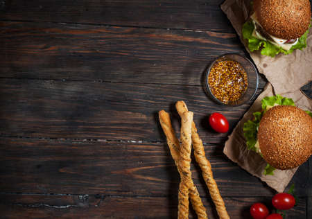 Fresh homemade burgers and breadsticks on wooden background.