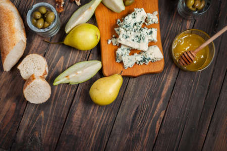 Blue cheese with honey, olive and pears on rustic table.の写真素材