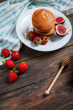 pancakes with figs, strawberries on white plate closeup.の写真素材