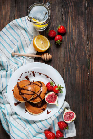 cup of tea and pancakes with figs, strawberries on white plate closeup.の写真素材