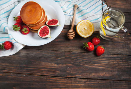 cup of tea and pancakes with figs, strawberries on white plate closeup.の写真素材