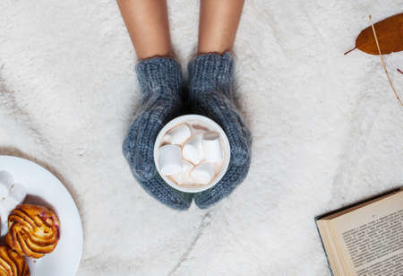 Hands in knitted mittens holding hot chocolate with marshmallow.の写真素材