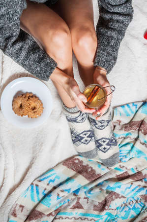 Long female feet in warm woolen socks with cup of tea.の写真素材