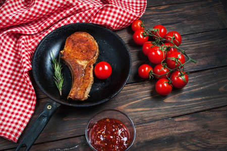 Steak in frying pan and cherry tomatoes on table close up.の写真素材