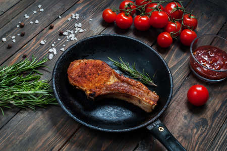 Steak in frying pan and cherry tomatoes on table close up.の写真素材