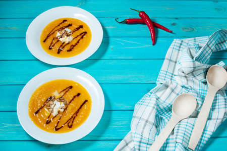 Two portions of pumpkin soup on a blue wood background.の写真素材