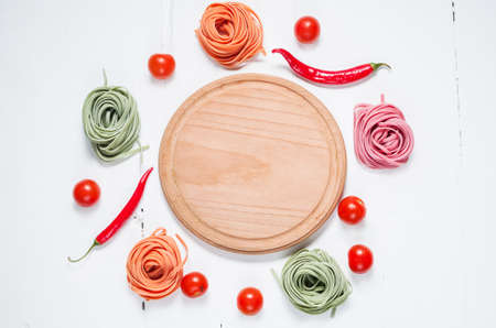 Colorful rolled pasta, cherry tomatoes on the white wooden background.の写真素材