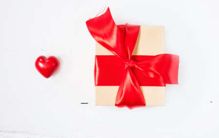 Gift or present box with red bow ribbon and ceramic heart on wooden table for Valentines day.の写真素材