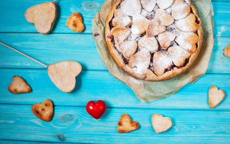 Idea for the celebration of Valentine's Day: cherry pie with the decor of the dough in the shape of heart on wooden table.の写真素材