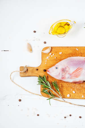 fresh tilapia on white wooden textured background with fresh rosemary and lemon. Culinary mediterranean seafood.の写真素材