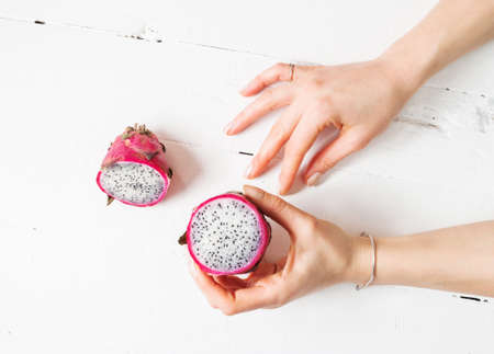 Female hands and Juicy pink pitaya on wooden table.の写真素材