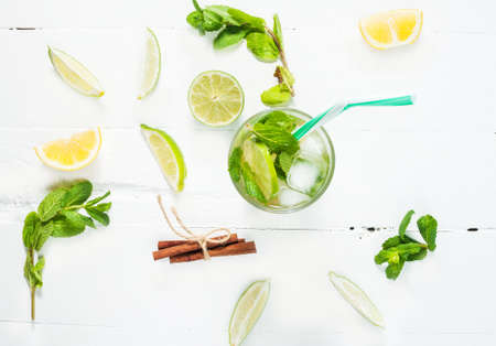 Mojito cocktail with lime and mint in highball glass on a wood white background. Top view