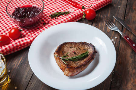 Grilled beef steak seasoned with spices served on a wooden board with fresh cherry tomato and red hot chili peppers.の写真素材