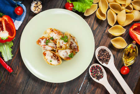Raw Conchiglioni with minced meat and vegetables on dark wooden background.の写真素材