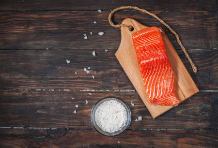 Salmon filet with salt on a wooden carving board. Top viewの写真素材