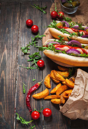 hot dog on board with sauce and french fries on a wooden tableの写真素材