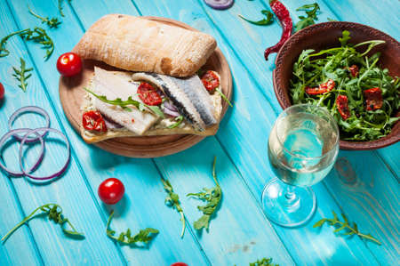 sandwiches with herring and salad with arugula on blue wooden table.の写真素材