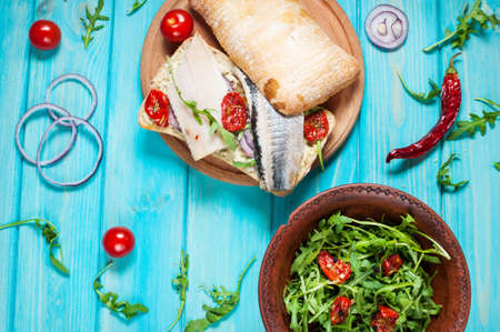 sandwiches with herring and salad with arugula on blue wooden table.の写真素材
