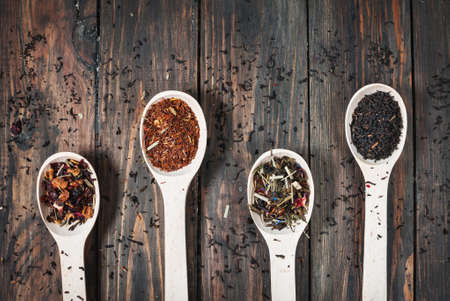 Different kinds of tea in wooden spoons on wood table. Top viewの写真素材