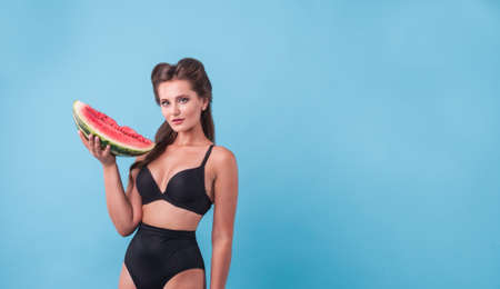 Picture of young woman holding a big slice watermelon in the studio. Copyspaceの写真素材