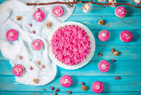 Cake and cupcakes with pink cream on blue wood background. Pink cakes. Top viewの写真素材