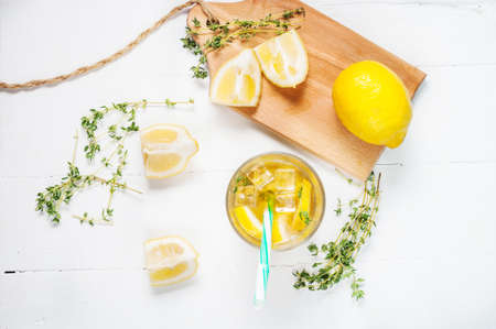 lemonade with thyme served in glass with a straw on a white wooden table. Top viewの写真素材