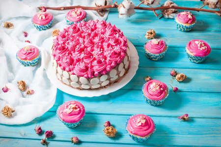 Cake and cupcakes with pink cream on blue wood background. Pink cakesの写真素材