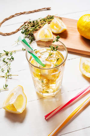 lemonade with thyme served in glass with a straw on a white wooden tableの写真素材