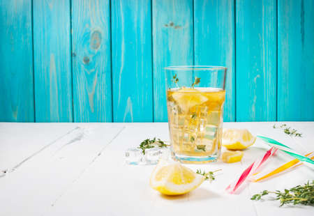 lemonade with thyme served in glass with a straw on a white wooden table. Copyspace and text placeの写真素材