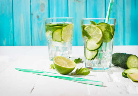 Cold and refreshing infused detox water with lime, mint and cucumber in a glass on wood background.の写真素材