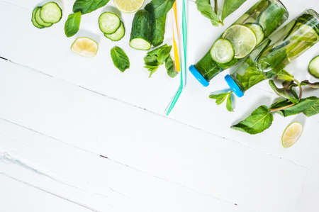 Cold and refreshing infused detox water with lime, mint and cucumber in a bottle on white wood background. Copyspace and top viewの写真素材