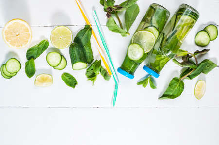 Cold and refreshing infused detox water with lime, mint and cucumber in a bottle on white wood background. Copyspace and top viewの写真素材
