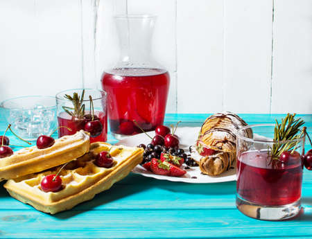 Breakfast : waffles and croissant with blueberries, cherries and strawberries. Stewed fruit in glasses and decanterの写真素材