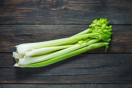 Fresh green celery vegetable on wood. Top view. Organic background.
