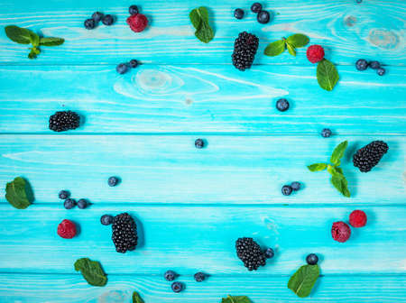 Fresh summer berries, corner frames on blue wooden background, top view