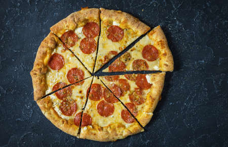 Pepperoni pizza on rustic, vintage style. Top view on dark stone table