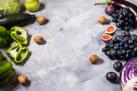 Fresh organic raw green and purple colored vegetables and fruits on stone background. Copyspaceの写真素材