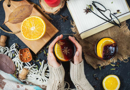Hot mulled wine in female hands, spices on dark stone table. Sweet-home concept. Top viewの写真素材