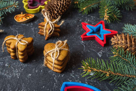 Christmas gingerbread cookies and fir tree and cones on dark stone backgroundの写真素材