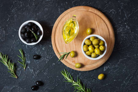 Black and green olives in wooden bowls on stone black background. Top viewの写真素材