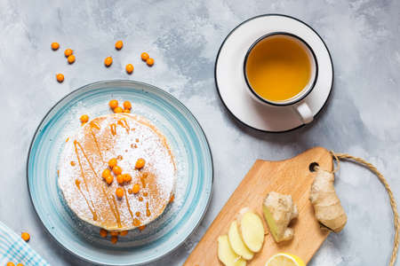 Home-made breakfast: american style pancakes served with berries and sugar powderwith a cup of tea...